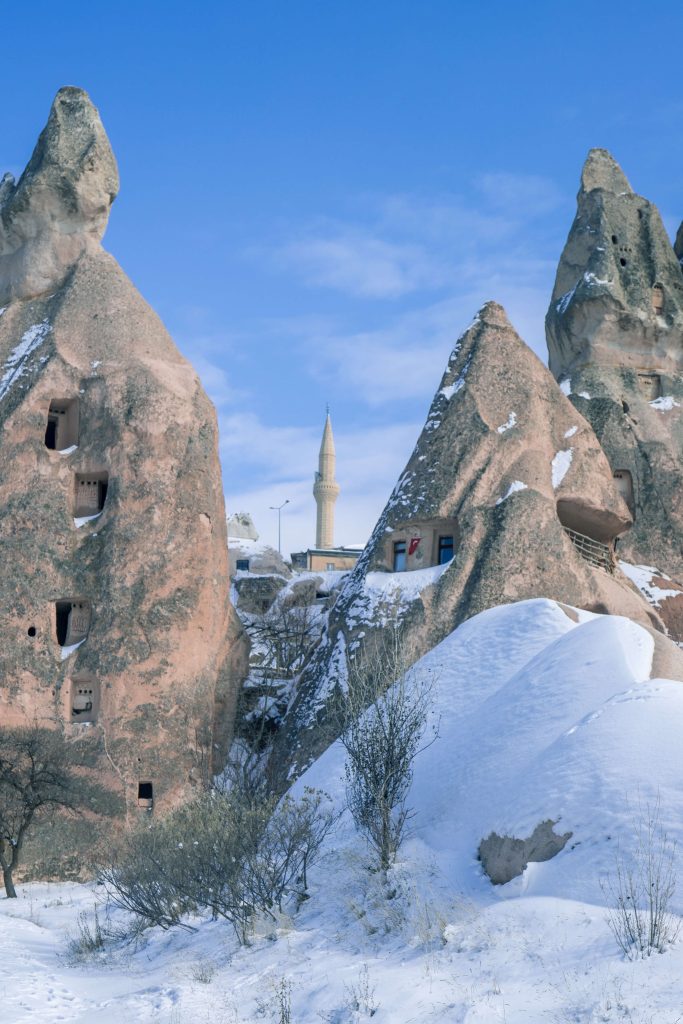 Tussen de schoorstenen van Uchisar Cappadocië is een minaret zichtbaar
